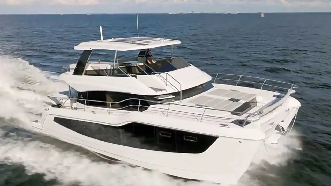 White luxury motor yacht speeding across the sea, leaving a foamy wake, with a person at the helm.