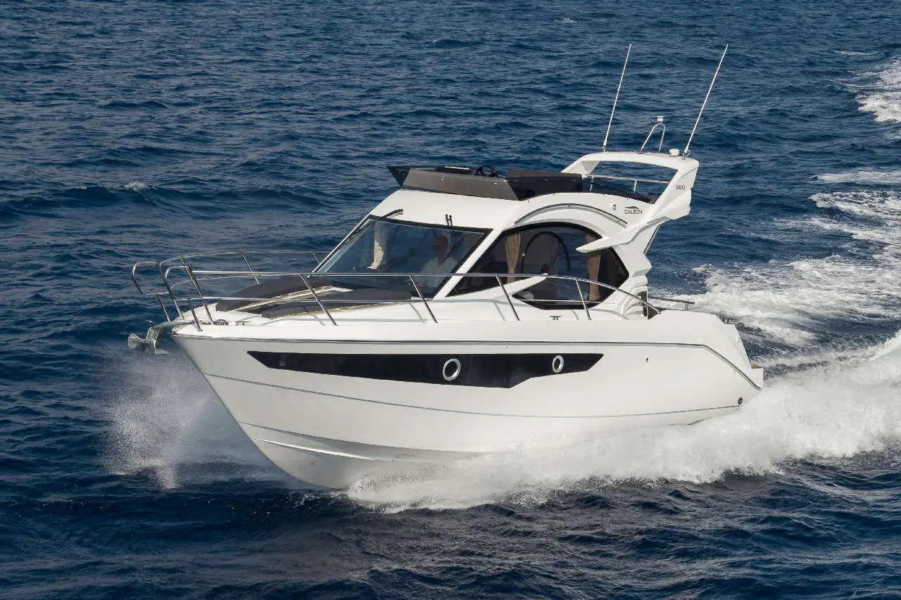 A sleek white luxury boat navigates through deep blue waters, creating splashes while in motion.