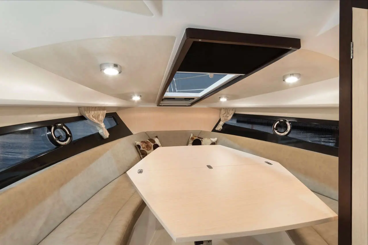 Interior of a modern yacht featuring a spacious seating area with cushions and a central table under a skylight.