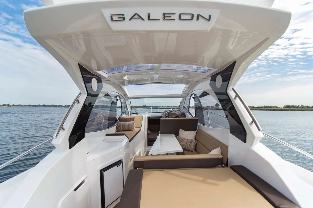 Modern yacht interior featuring seating, table, and panoramic view of water, labeled 