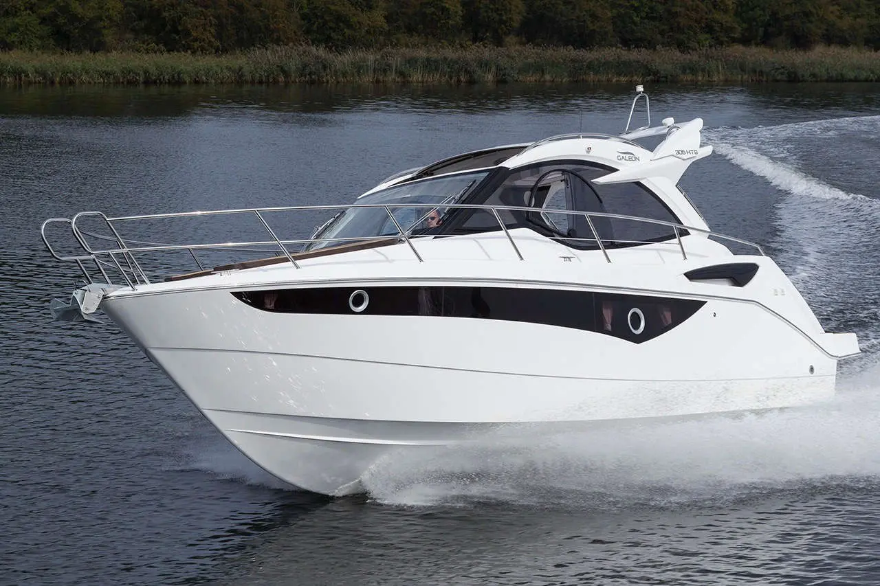 A sleek white motorboat glides across the water, creating splashes, surrounded by greenery, highlighting luxury and leisure.