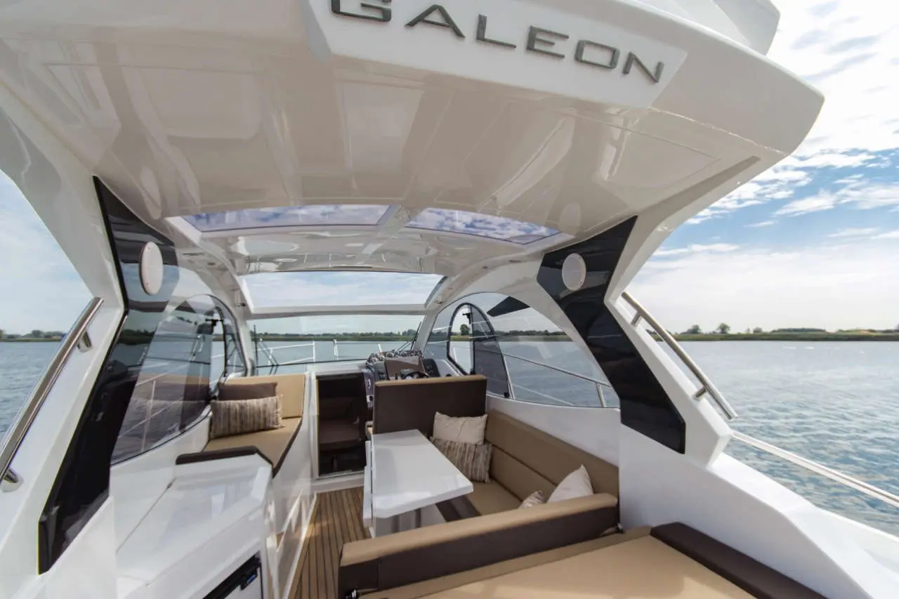 Interior of a Galeon yacht featuring modern seating, a table, and panoramic views of the water and sky.