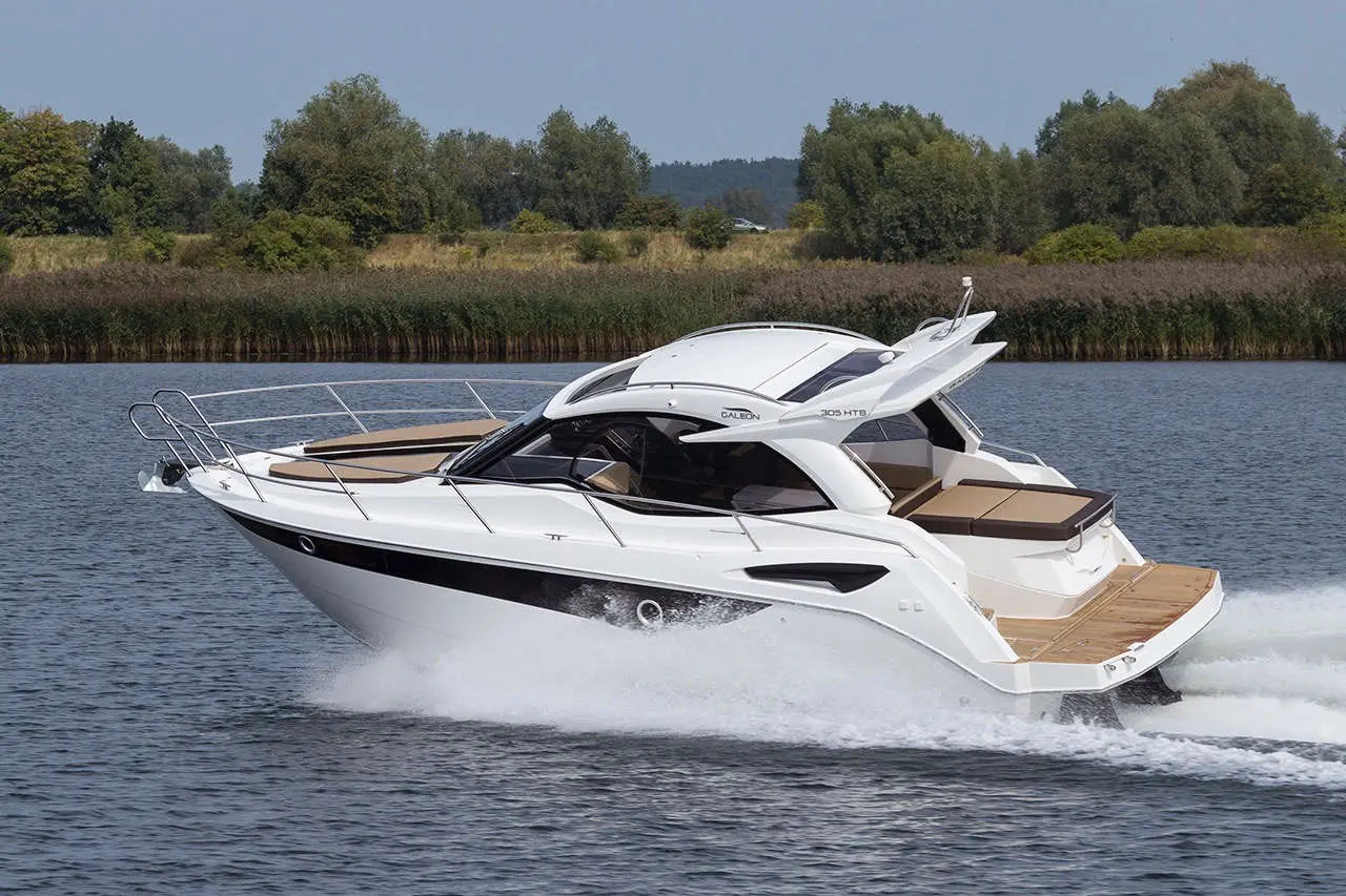 A sleek Galeon 305 HTB motorboat cruising on calm waters, showcasing its modern design and spacious rear deck.