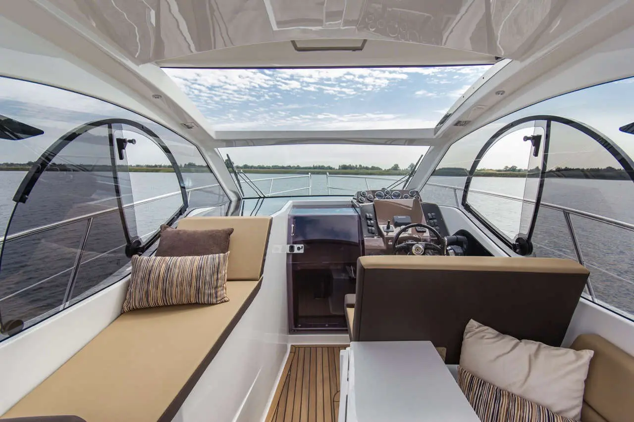 Luxurious boat interior featuring a dashboard, comfortable seating, and a view of the water and sky. Ideal for leisure cruising.