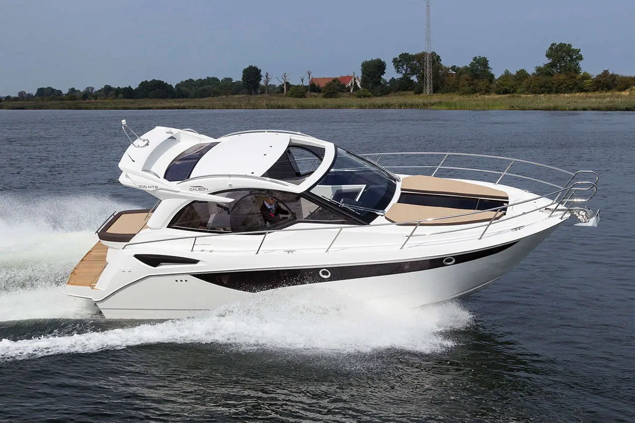 A sleek white motorboat cruising on calm waters with a scenic green shoreline in the background.