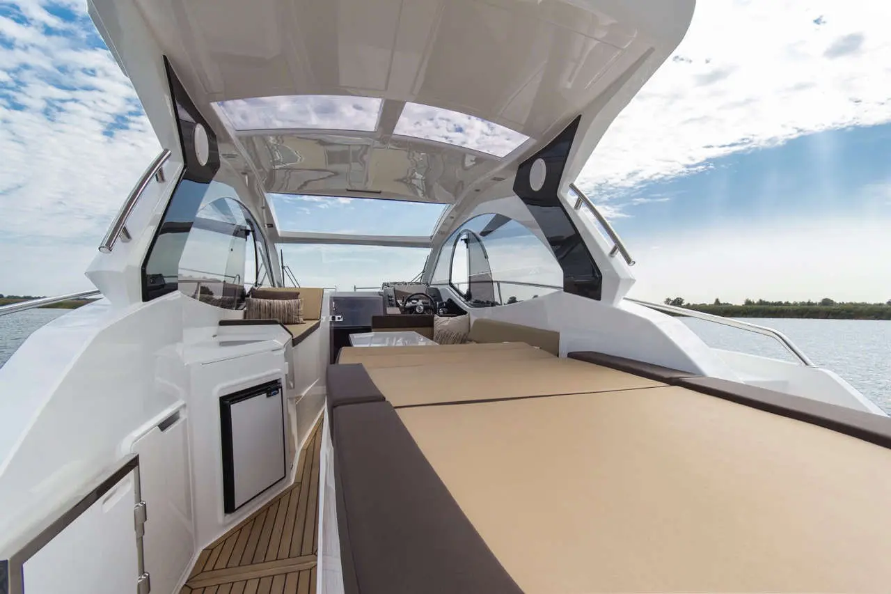Luxury yacht interior featuring a spacious seating area, helm, large windows, and panoramic views of the water.