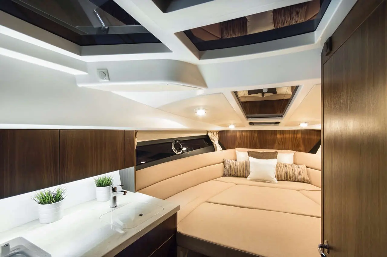 Modern yacht interior featuring a cozy seating area, light wood accents, and skylights. Soft furnishings enhance comfort.
