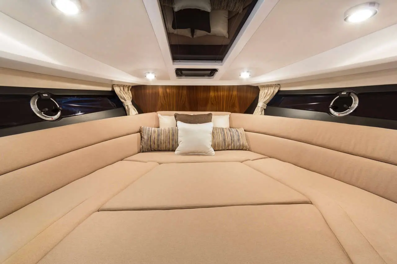 Spacious yacht interior featuring a beige seating area with decorative cushions and natural light from a skylight above.