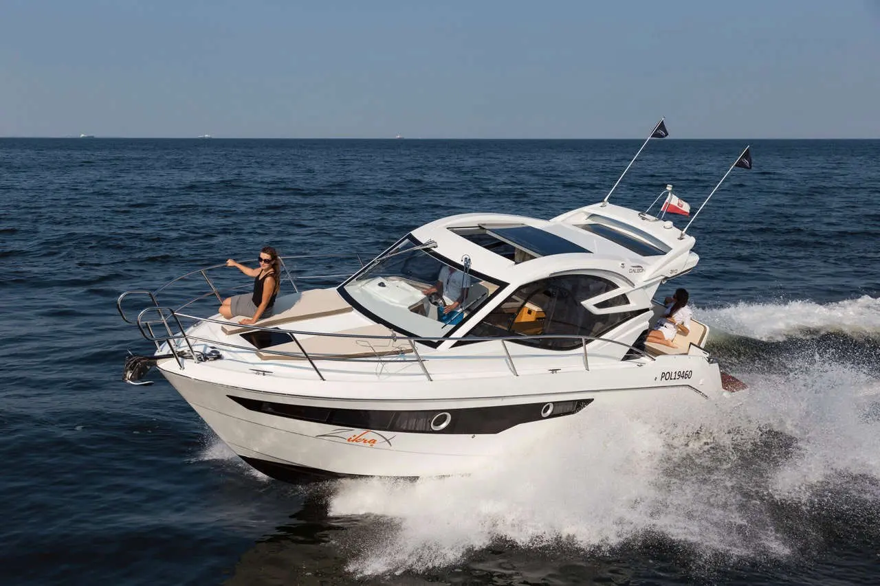 A white motorboat speeds across the water, with two women on board enjoying the ride, one relaxed at the front.