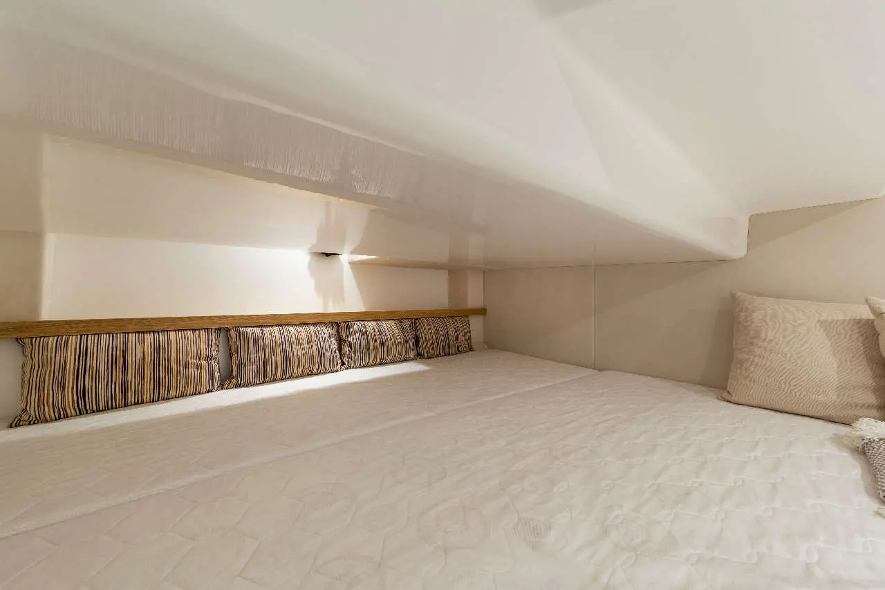 Cosy bedroom featuring a plush mattress, striped cushions, and ambient lighting in a minimalist, modern design.