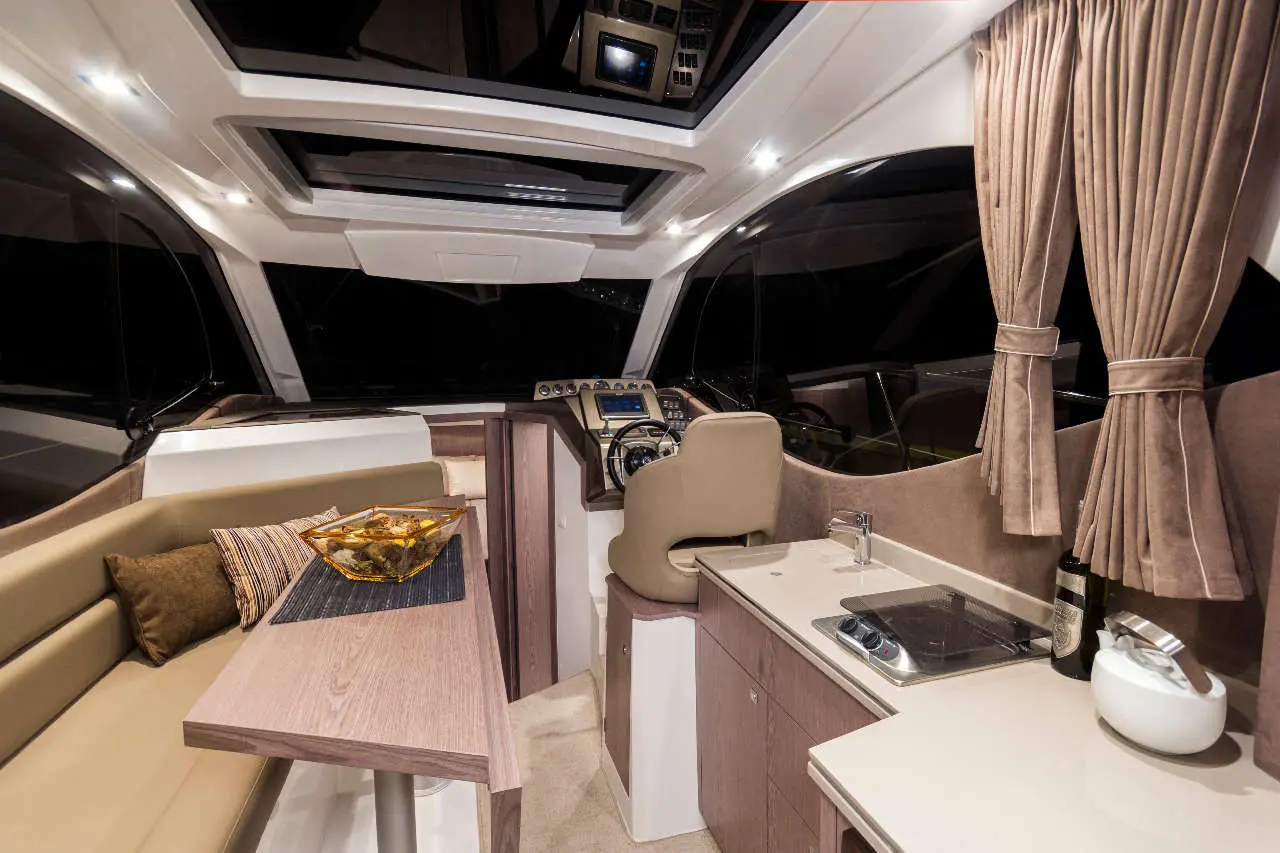 Luxury boat interior featuring a seating area, galley, and navigation controls with ambient lighting and decorative bowl.