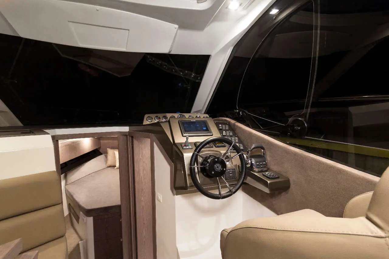 Interior of a modern boat cockpit featuring a steering wheel, navigation controls, and a comfortable seating area.
