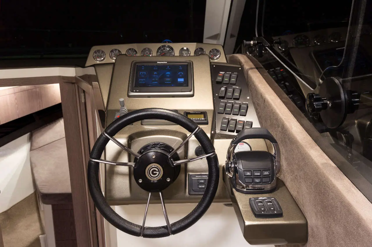 Boat cockpit featuring a steering wheel, digital display, control buttons, and marine equipment in a sleek design.