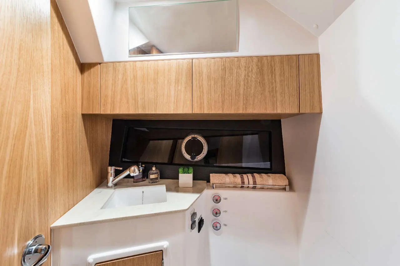 Modern bathroom with wooden cabinetry, white sink, mirror, decorative plants, and stylish accessories against a sleek design.