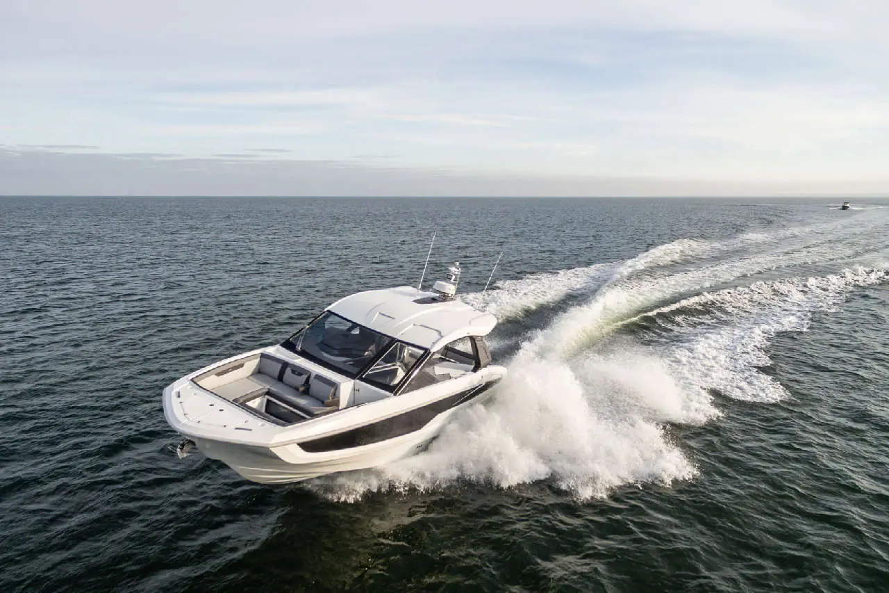 Speedboat cruising through turquoise waters, with waves splashing behind, under a clear blue sky.
