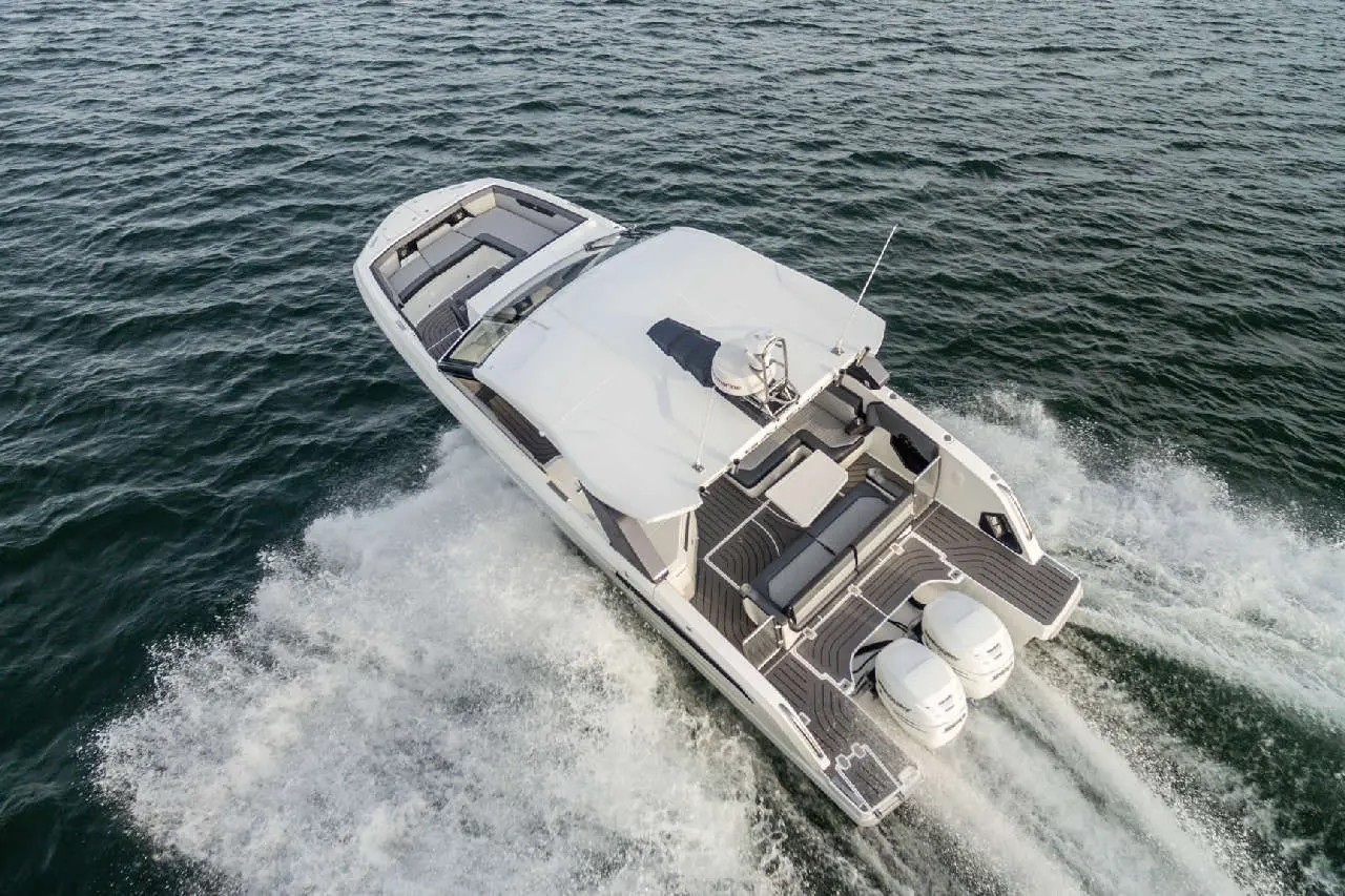 A luxury motorboat speeds across choppy water, showcasing sleek design and powerful twin engines at the rear.