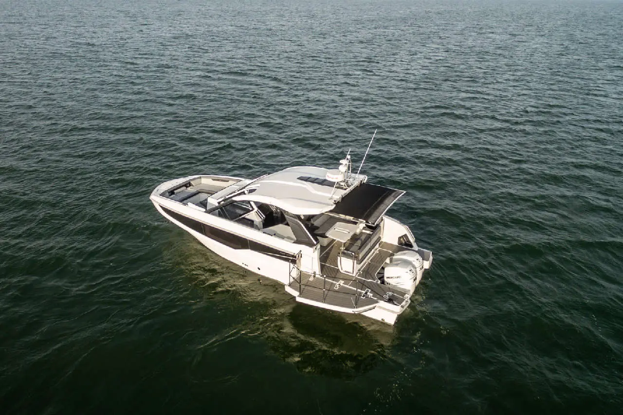 A sleek white motor yacht with a shaded deck floats on calm blue water. The boat features modern design elements and equipment.