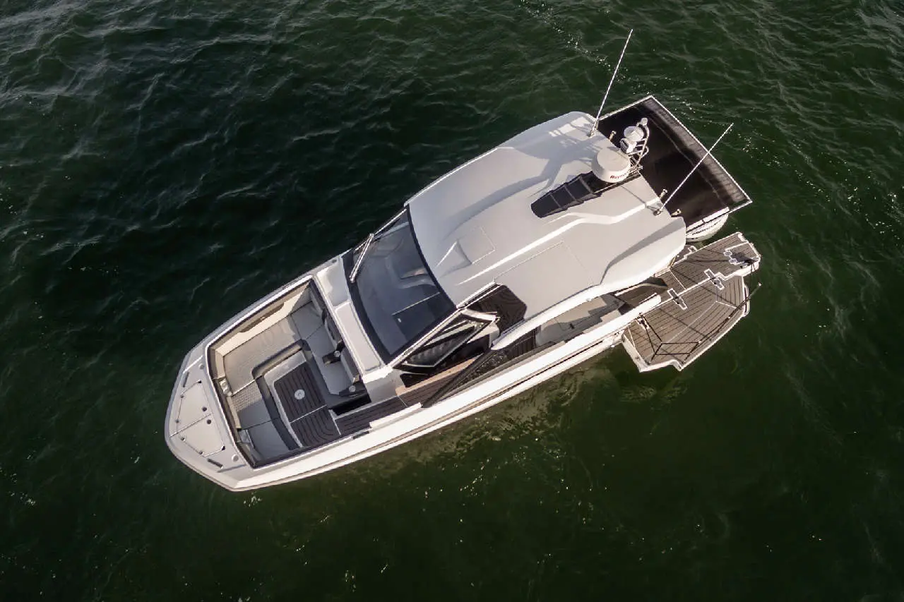 A sleek, modern motorboat with a spacious deck and seating, anchored on calm green waters.