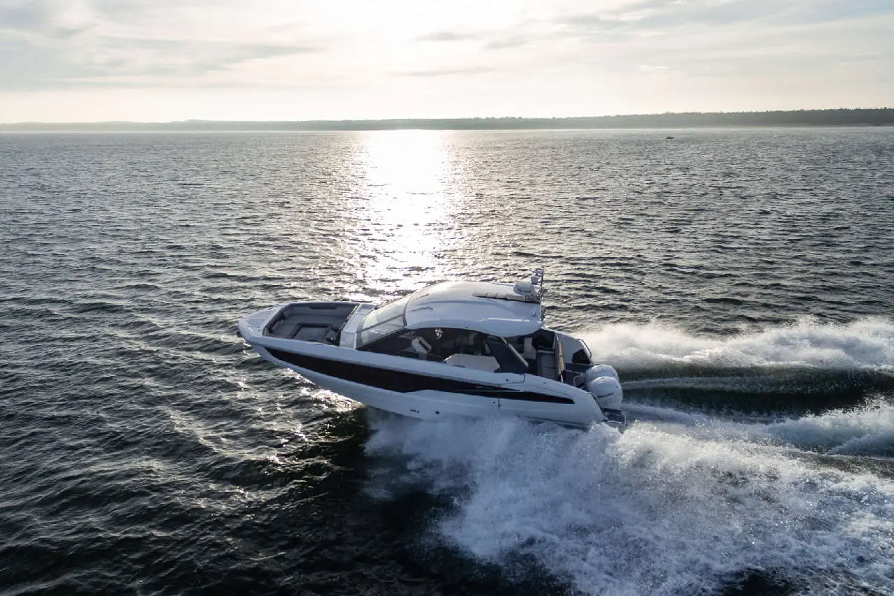 A luxury motorboat speeds across shimmering water under a bright sky, creating splashes and waves.