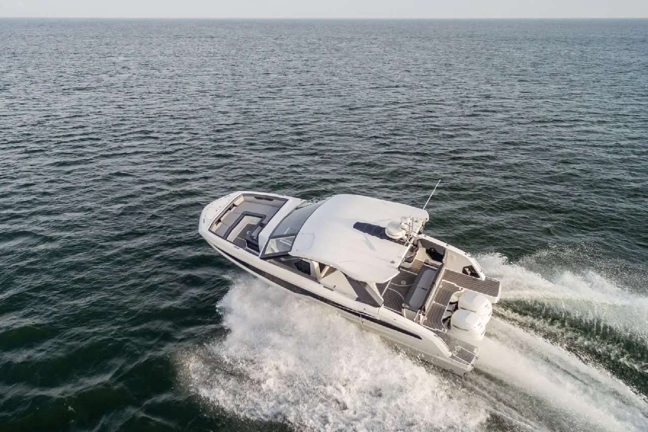A sleek white motorboat speeding across shimmering blue waters, leaving a frothy wake behind.