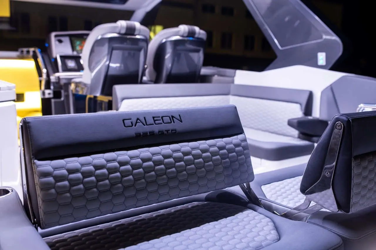 Interior of a Galeon 325 GTO boat, featuring stylish seating with hexagonal patterns and a modern dashboard in the background.