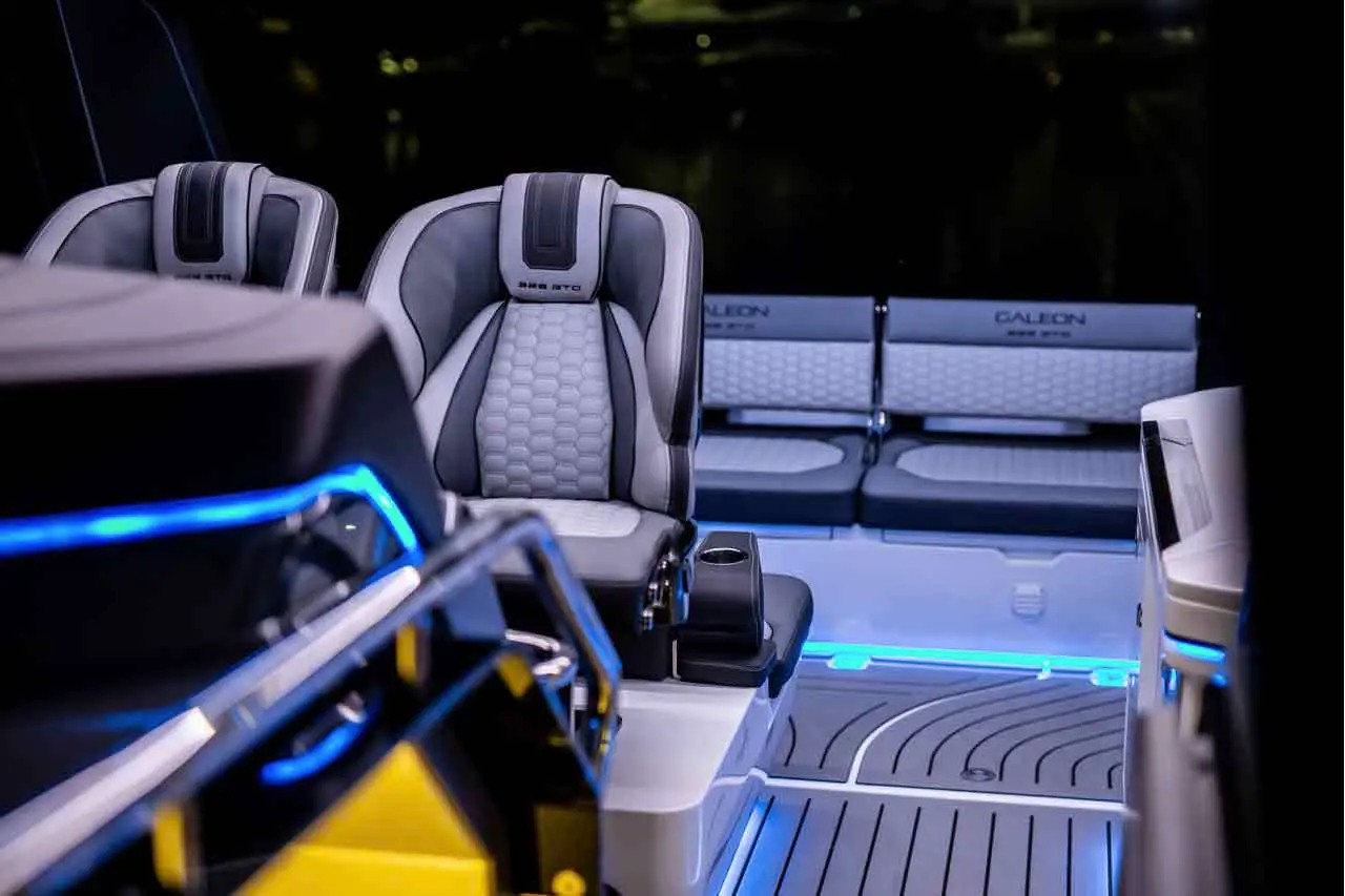 Luxury boat interior featuring comfortable grey and black seats, ambient blue lighting, and a stylish floor design.