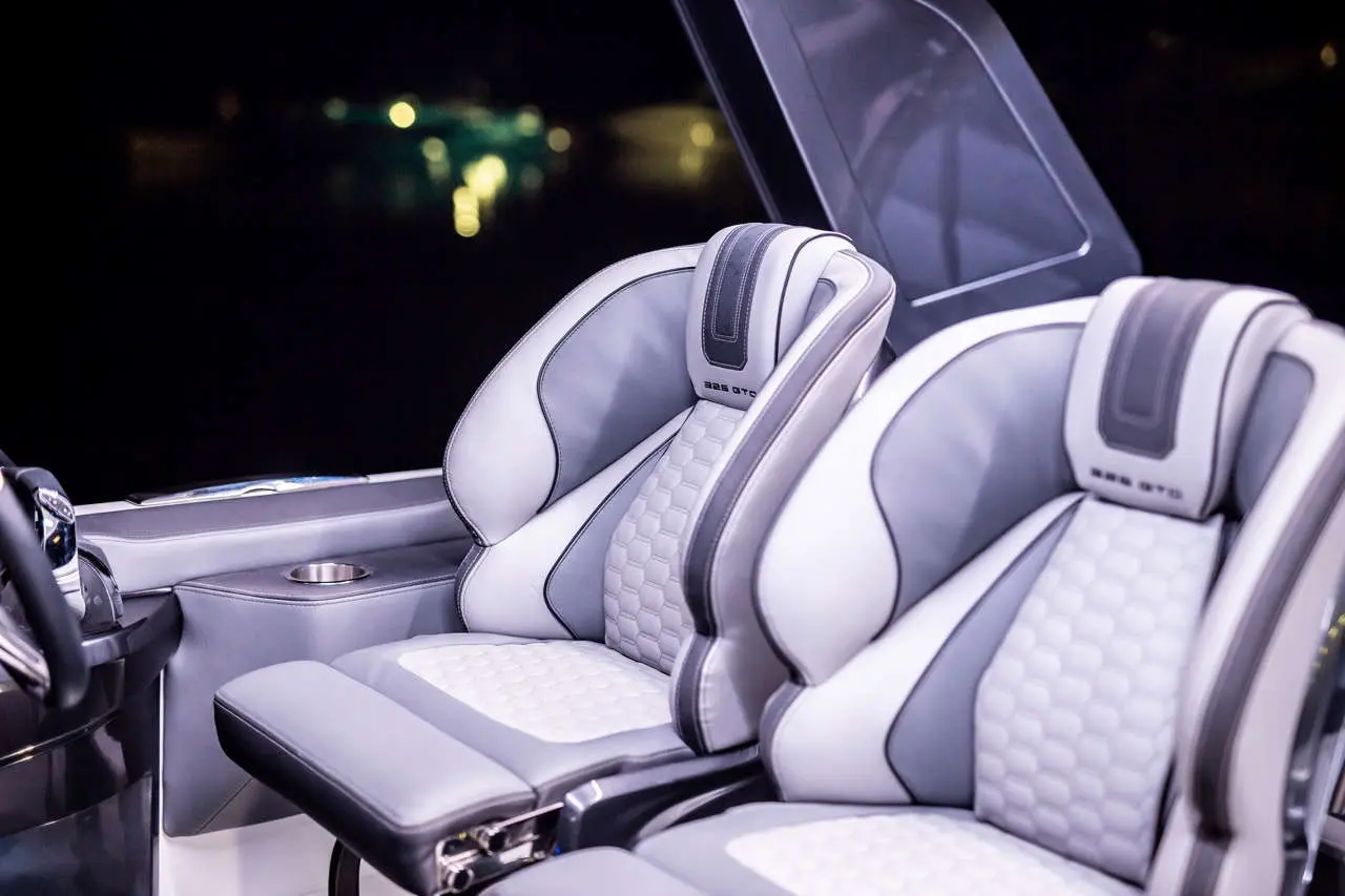 Modern boat seats in a luxury vessel, featuring grey and white upholstery, with ambient light reflecting in the background.