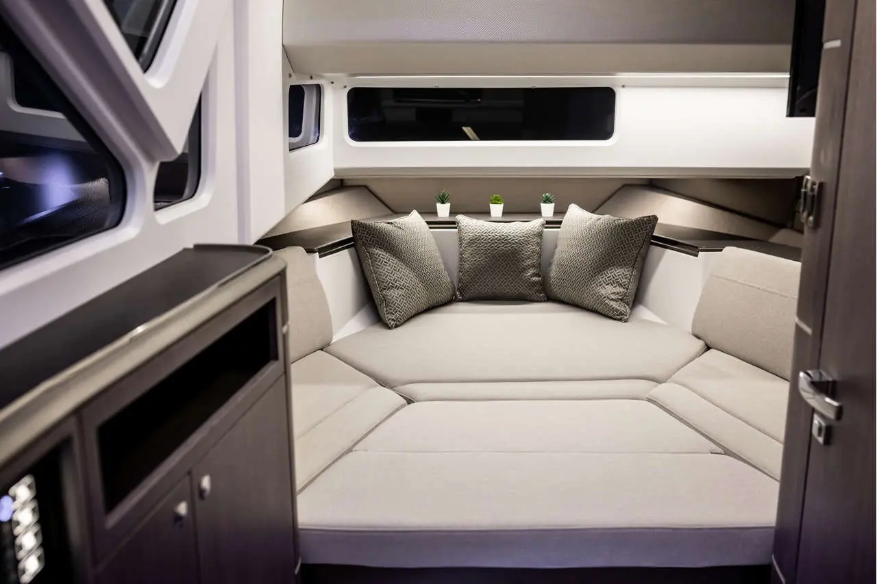 Modern interior of a boat cabin featuring a plush corner seating area with decorative cushions and small potted plants.