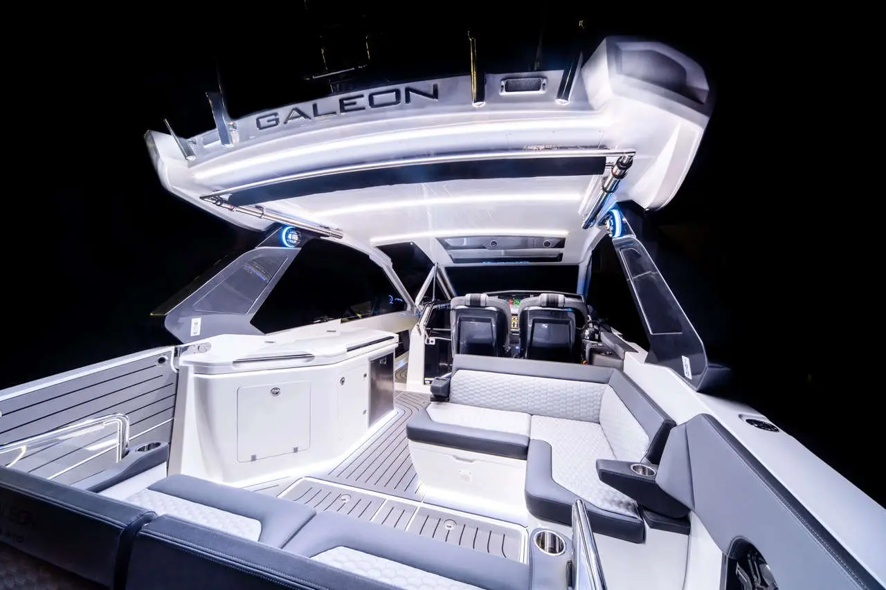 Interior of a modern Galeon boat, featuring stylish seating, a sleek dashboard, and illuminated surfaces against a dark background.