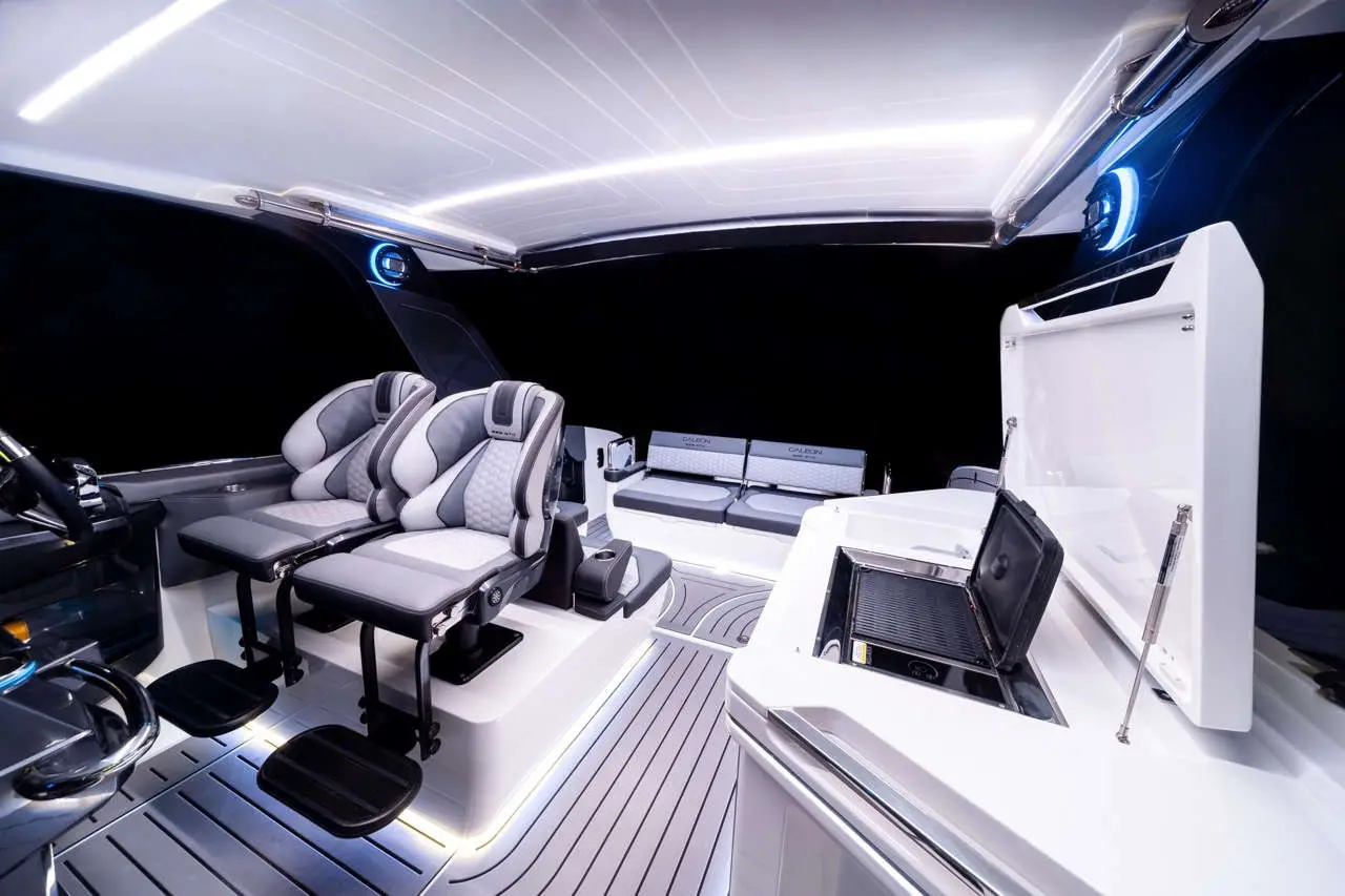 Modern boat interior featuring two ergonomic grey seats, sleek counter, and illuminated controls against a dark backdrop.