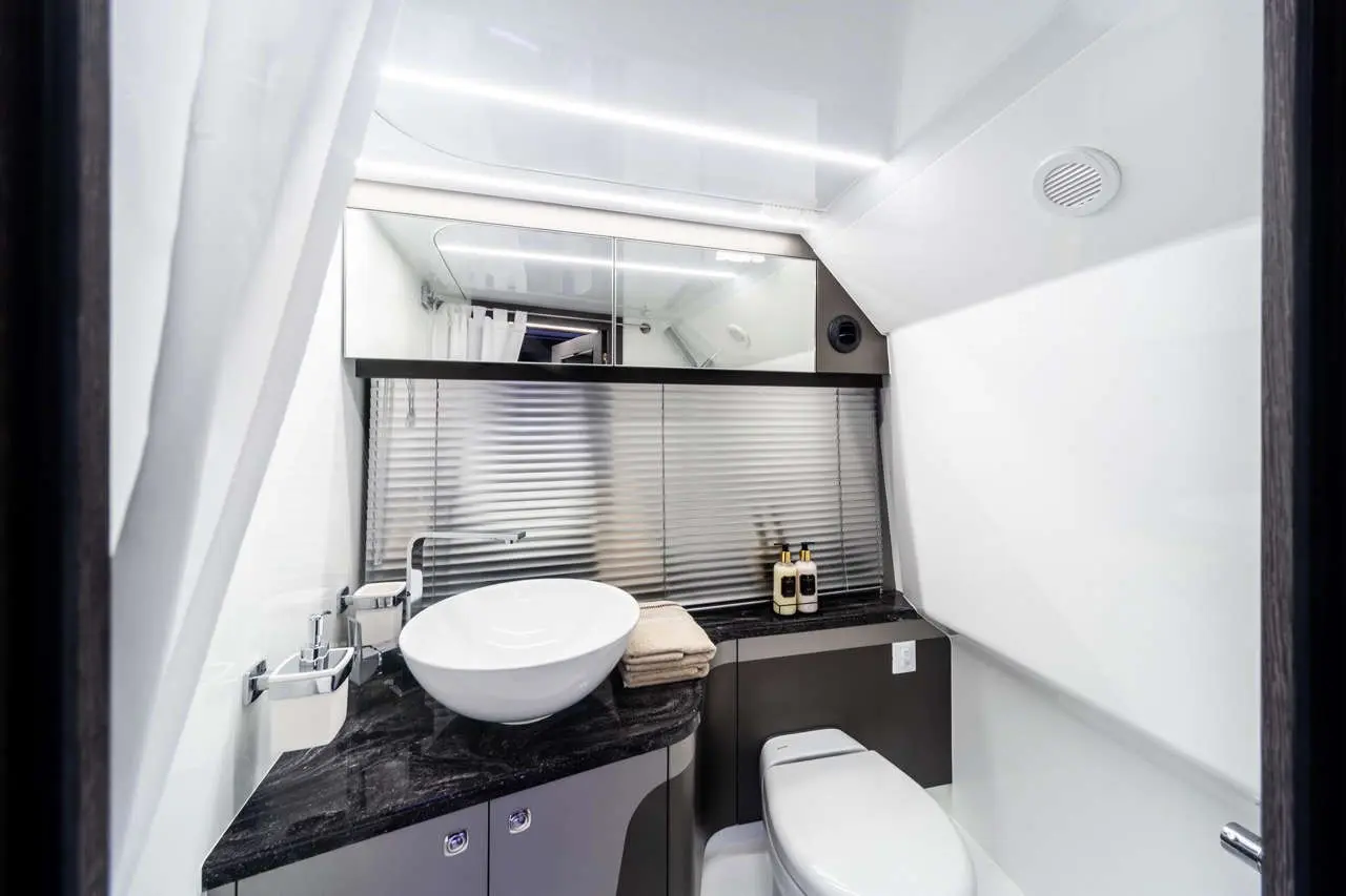 Modern bathroom interior featuring a bowl sink, sleek black countertop, and amenities like toiletries and towels.