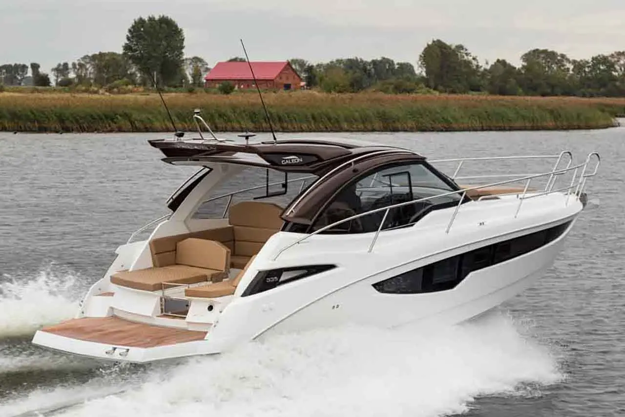 A sleek white motorboat accelerates through water, showcasing a luxurious seating area and verdant riverside landscape.