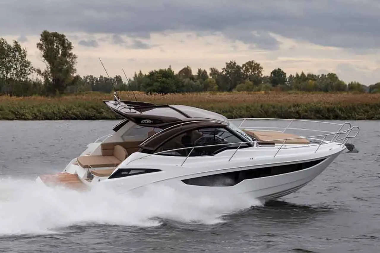 A sleek white powerboat speeds across a calm river, showcasing its modern design and spacious seating area.