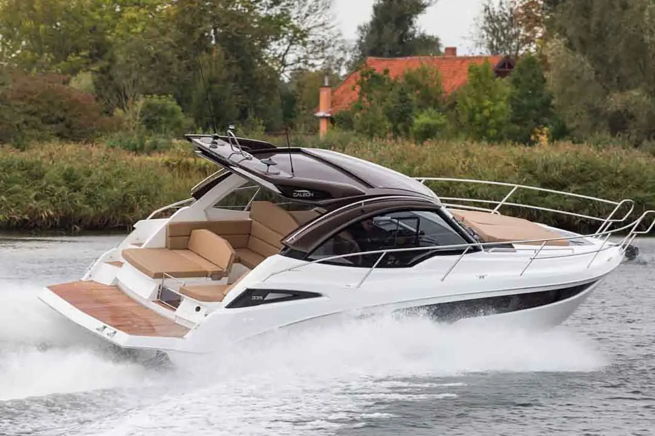 A sleek motorboat speeds across a river, accented by lush greenery and a house in the background.