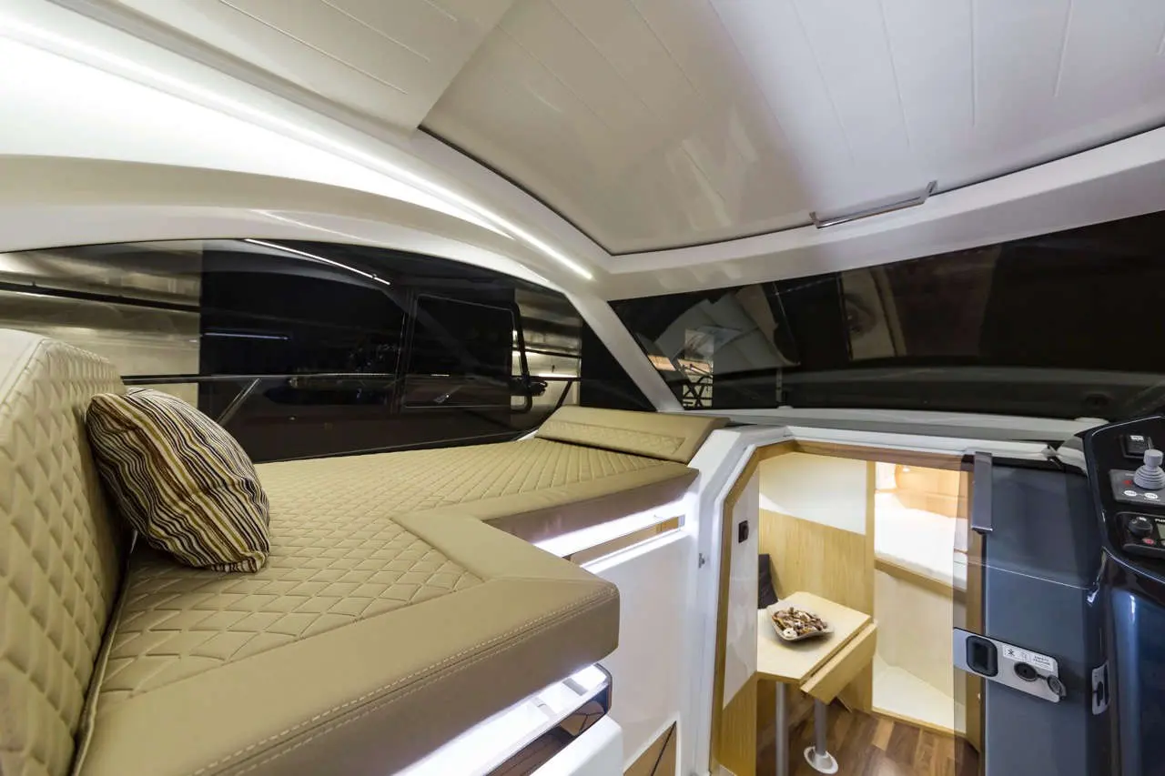 Luxurious boat interior featuring a comfy cushioned seating area and a small kitchenette with light wood accents.