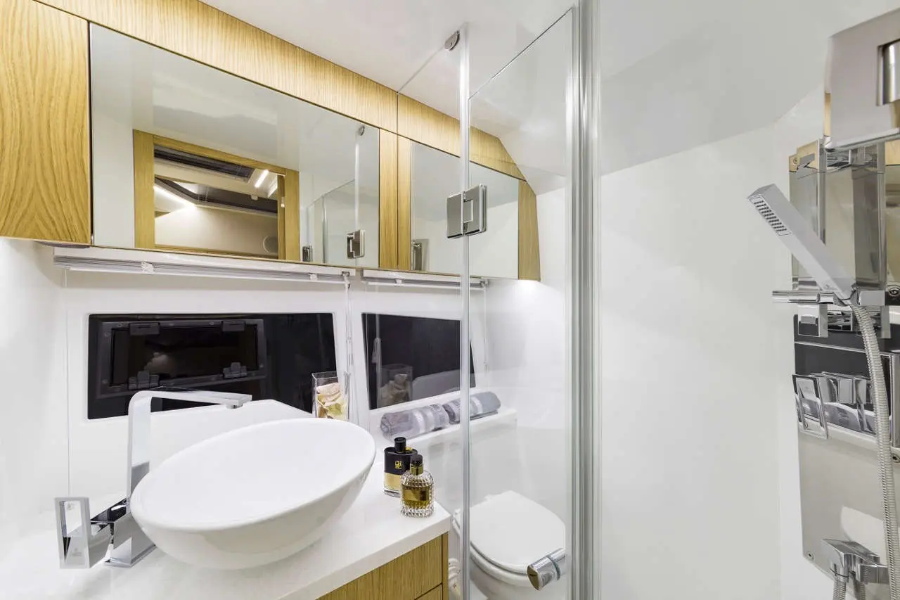 Modern bathroom featuring a vessel sink, wooden cabinetry, glass shower enclosure, and stylish toiletries on the counter.