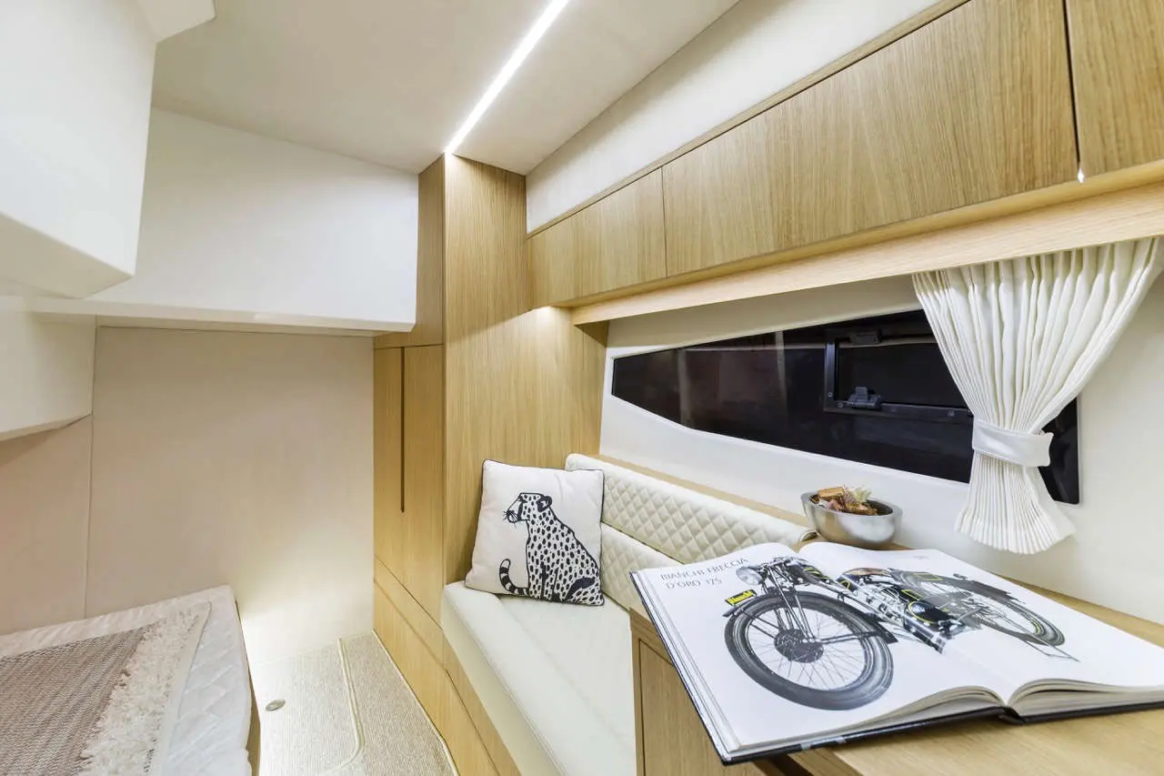 Cozy interior of a modern cabin with a bike book, sofa, decorative pillow, and warm wooden cabinetry, illuminated softly.