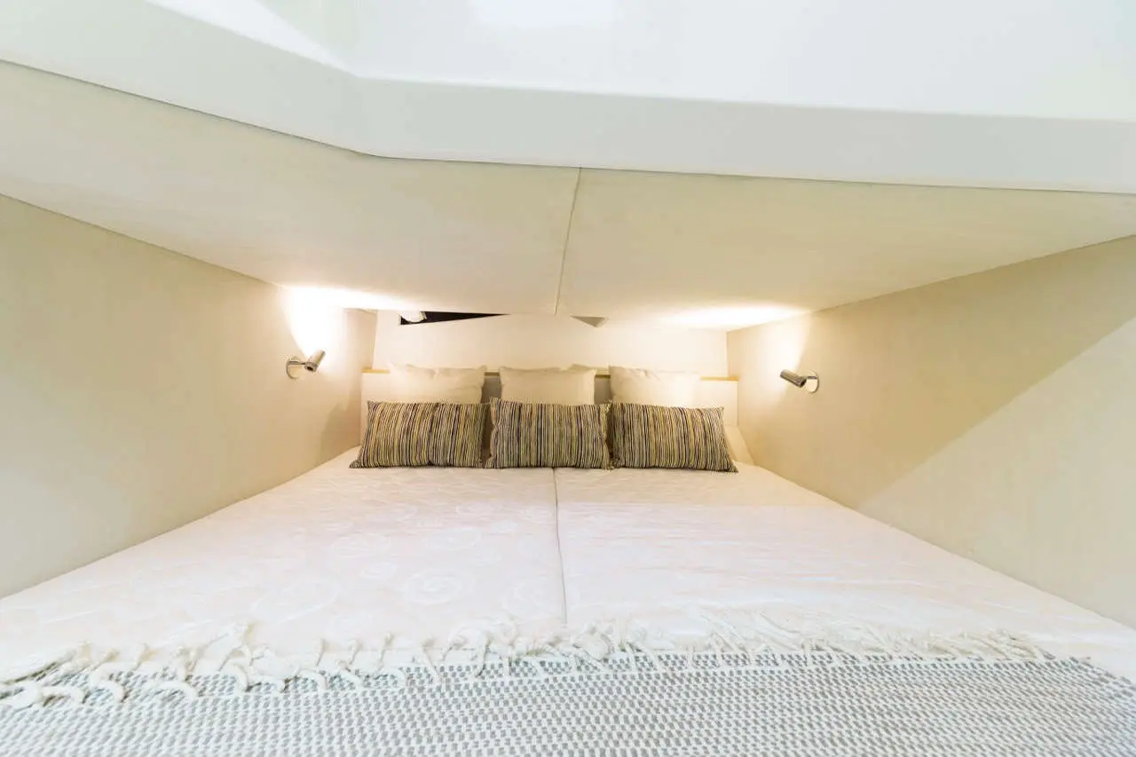 Cozy sleeping area under a sloped ceiling, featuring a white bedspread, striped pillows, and soft lighting.