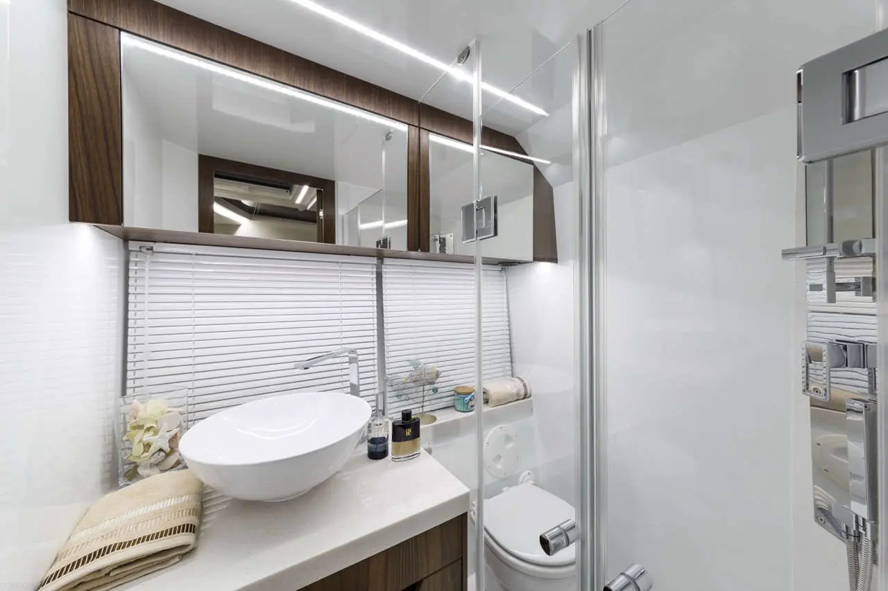 Modern bathroom with a round sink, shower, and decorative items on a countertop; features wood and white decor.