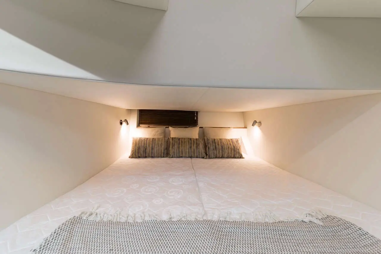 Cozy under-bed sleeping area featuring a large mattress, striped pillows, and soft lighting against a neutral backdrop.