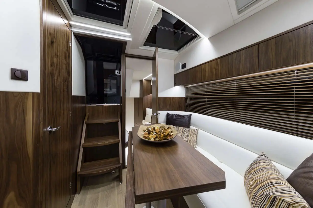 Luxury yacht interior showing wooden decor, a table with snacks, and a cozy seating area with soft cushions.