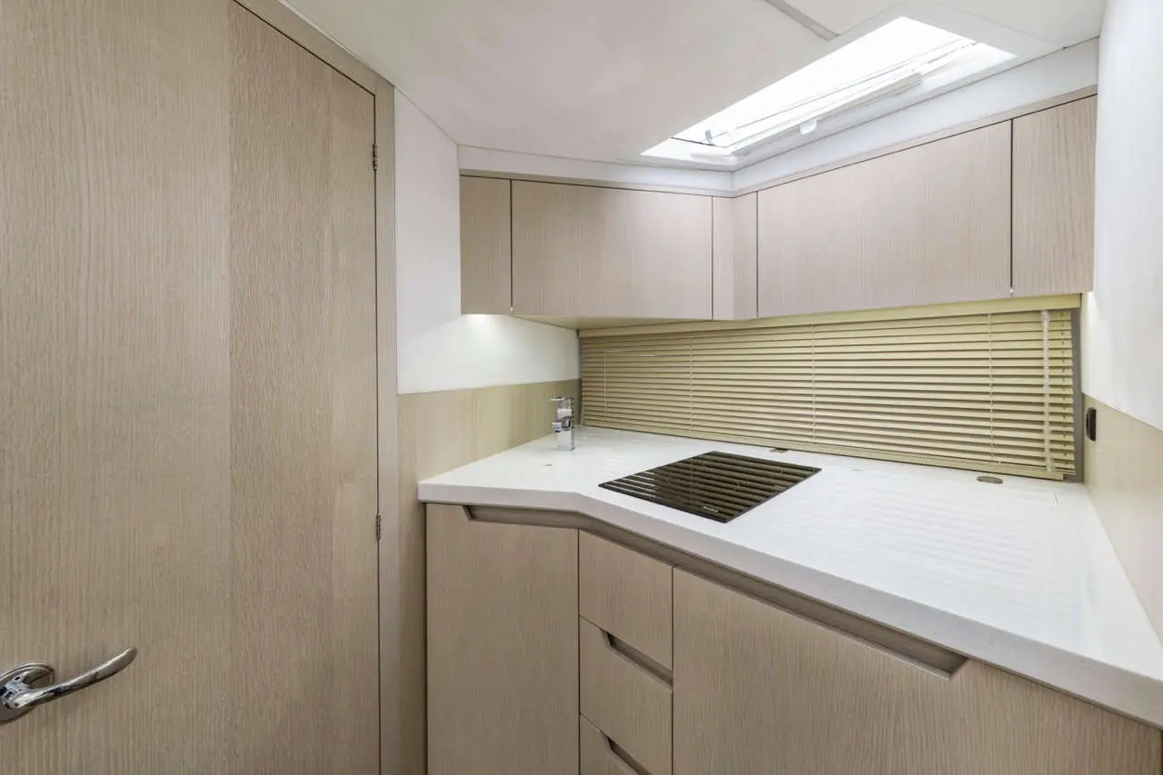 Modern kitchen with beige cabinetry, a white countertop, and a black stovetop, illuminated by natural light from a skylight.