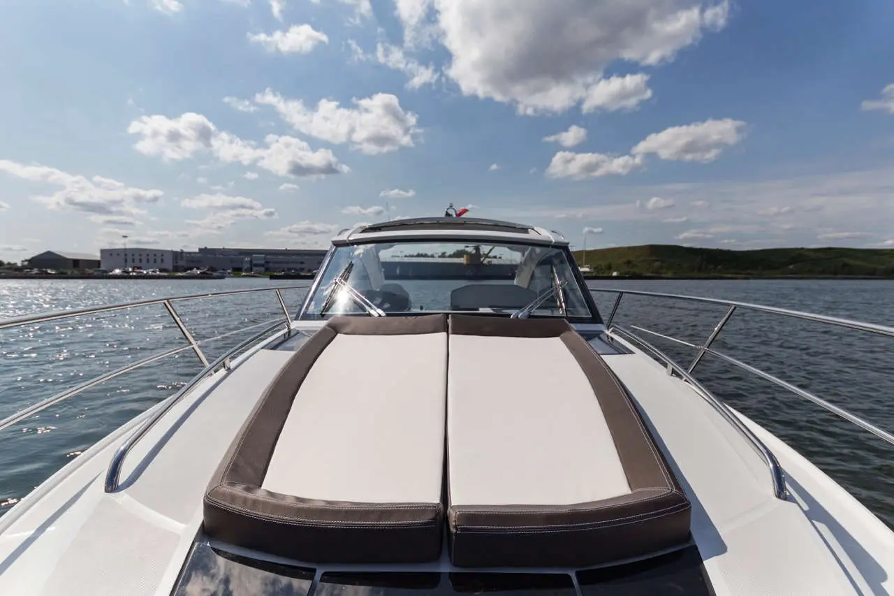 A luxury boat deck with cushioned seating, overlooking calm waters and a scenic cloudy sky.