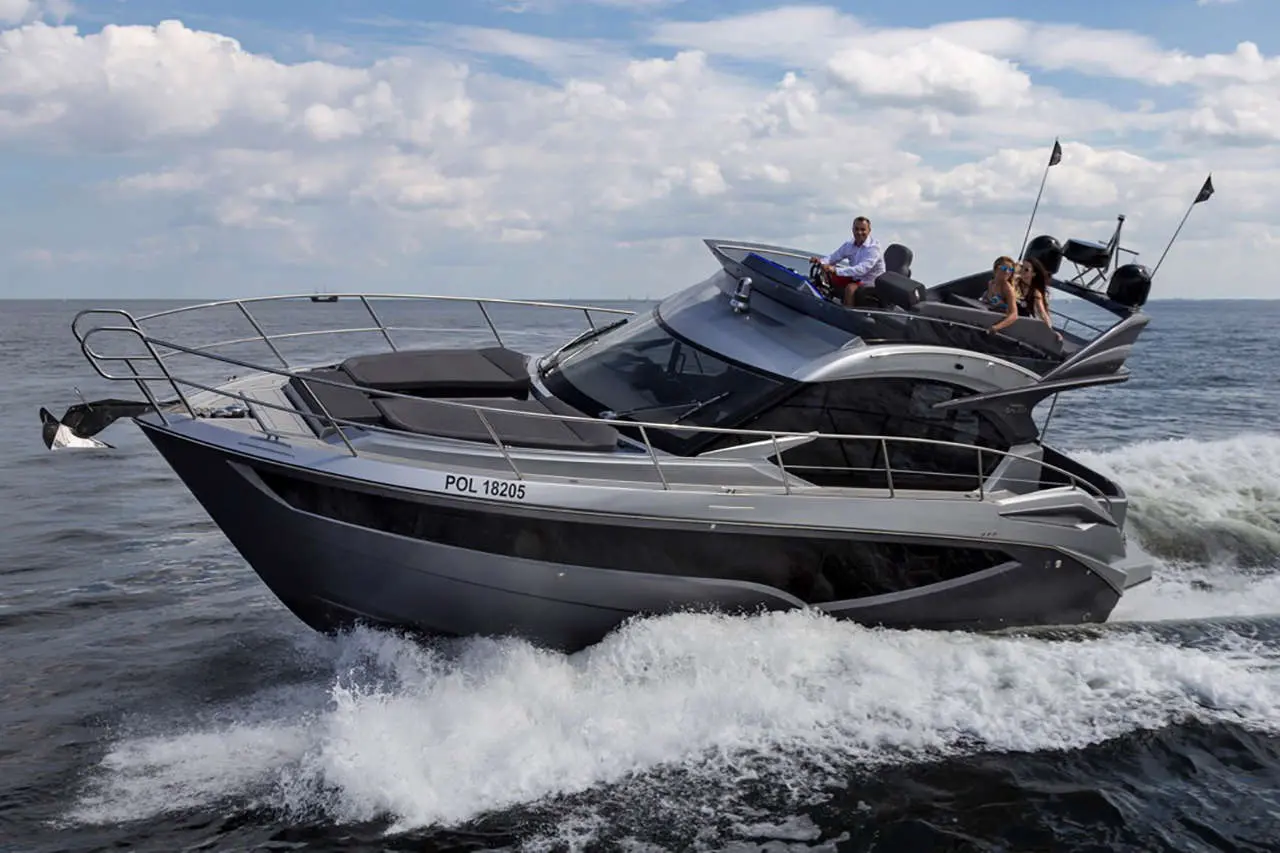 A sleek motorboat, marked POL 18205, speeds through waves with four people aboard, enjoying a day on the water.