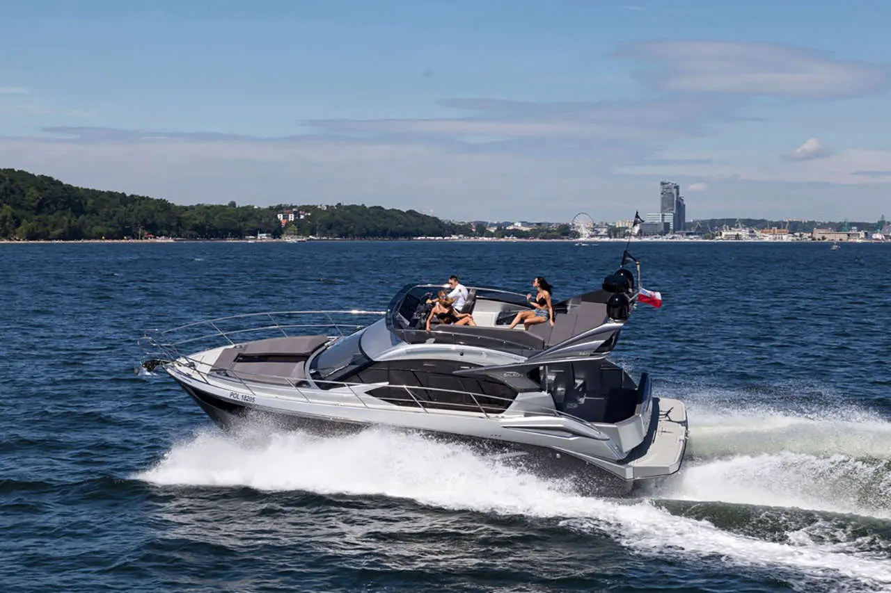 A sleek motorboat speeds through the water, with people enjoying the sun, set against a scenic coastal backdrop.
