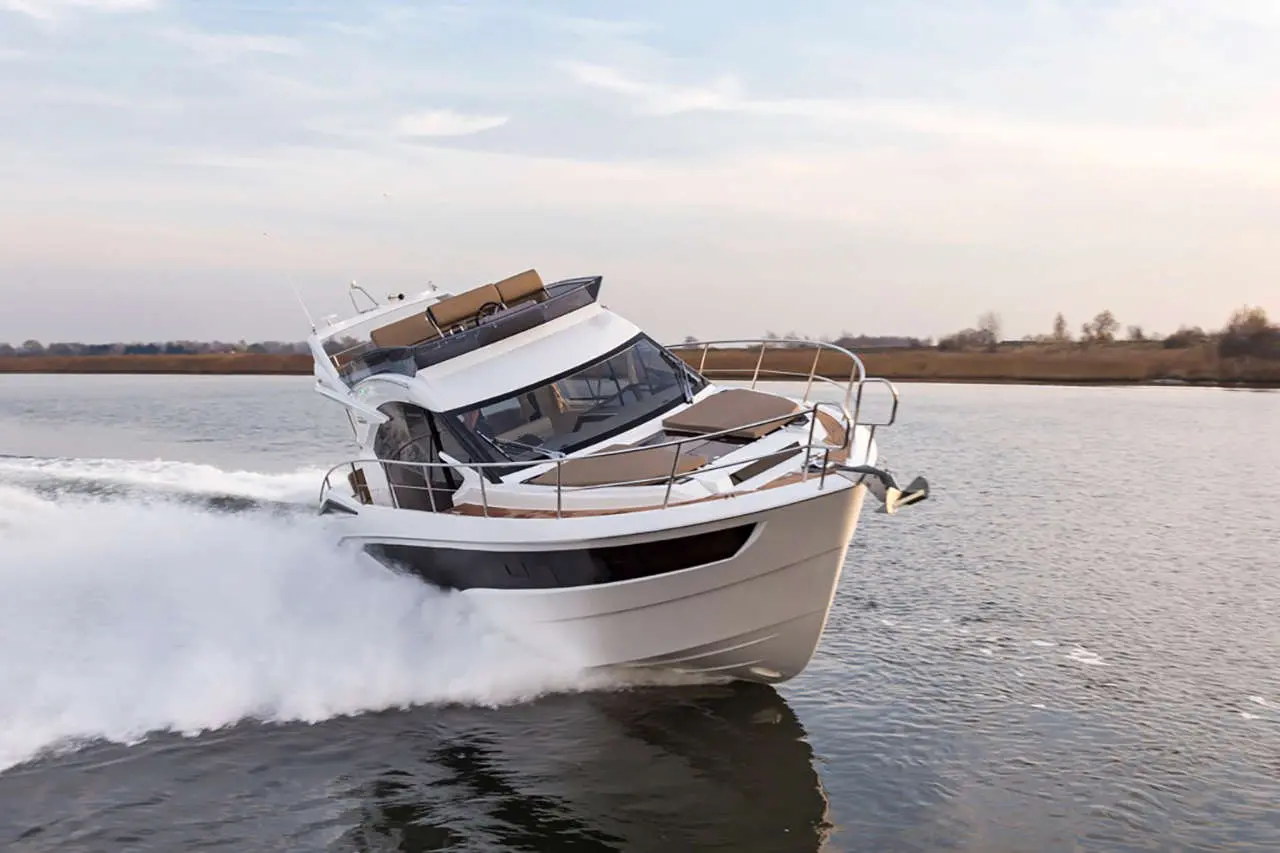 A sleek white motorboat cruising at high speed, leaving a spray of water behind on a calm river.