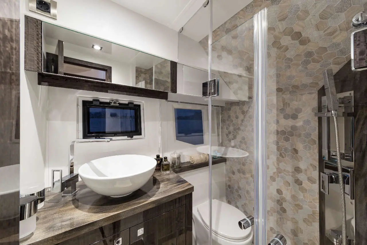 Modern bathroom featuring a circular basin, dark wood cabinetry, and textured hexagon tile, with a glass shower enclosure.