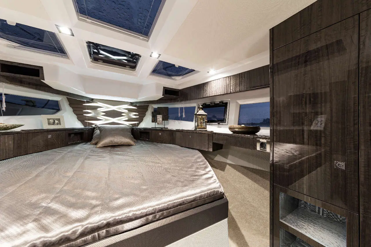 Luxurious modern bedroom on a yacht featuring sleek cabinetry, a spacious bed, and large skylights allowing natural light in.