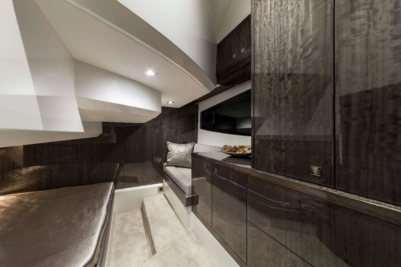 Modern yacht interior featuring dark wood cabinetry, a plush seat, and a display of snacks on a countertop.