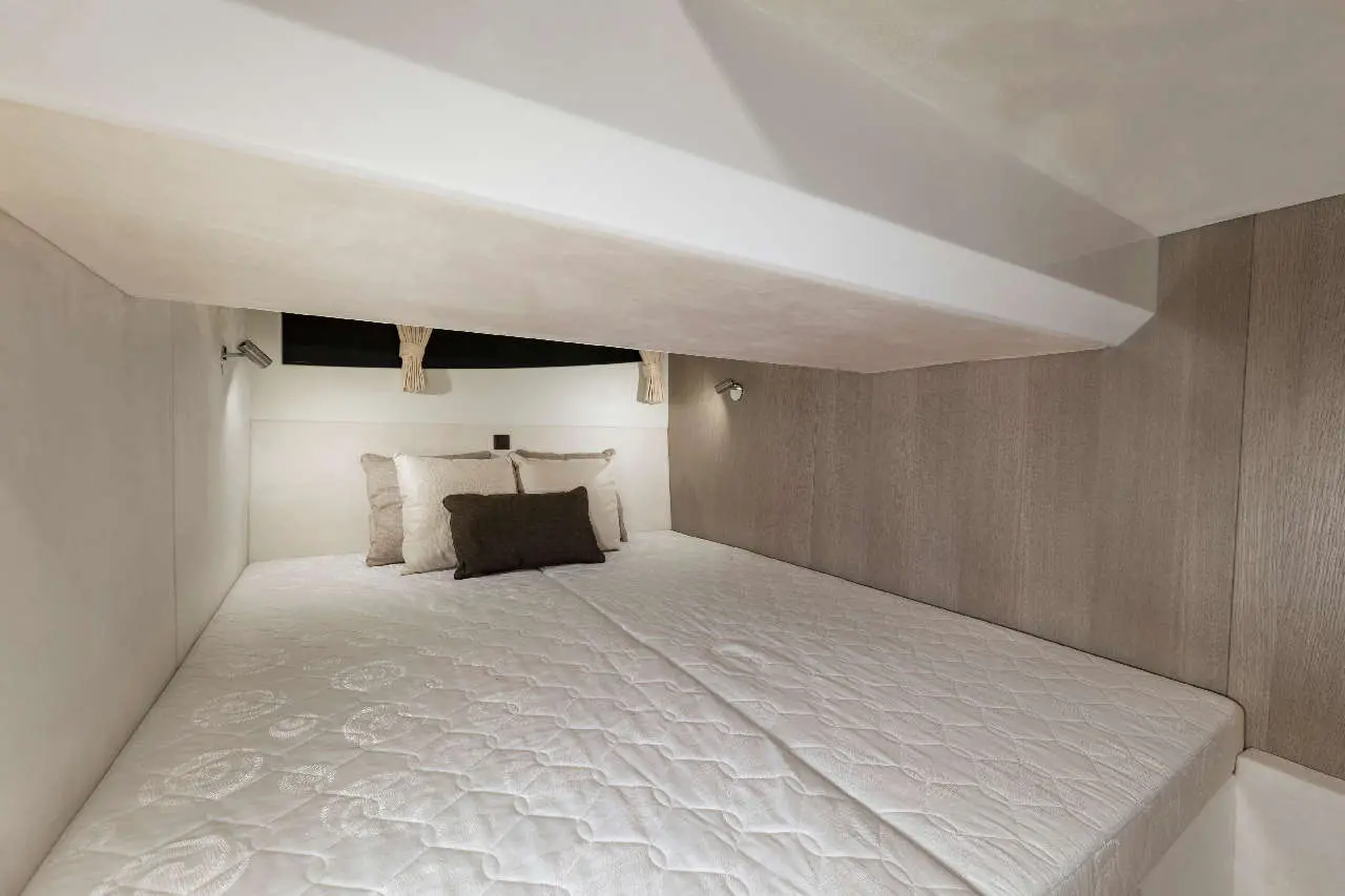 Small cabin interior featuring a double bed with white bedding, decorative cushions, and soft ambient lighting.